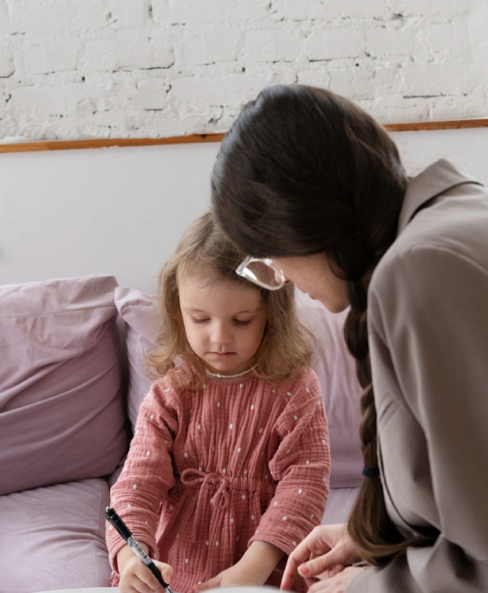 Adulte aidant une enfant lors d’une activité créative
