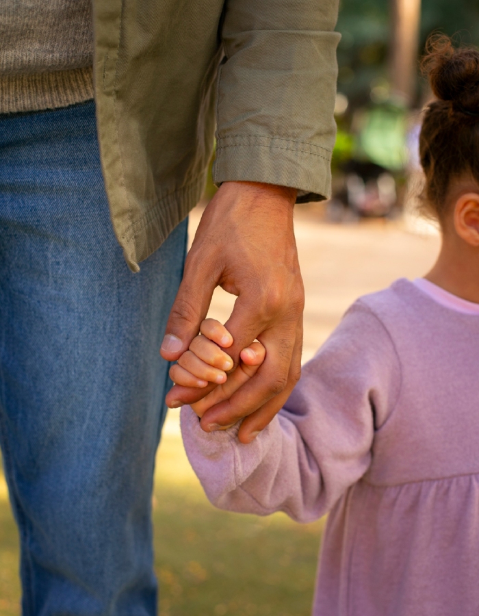 Parent tenant la main d’une enfant, symbole de la garde et de la responsabilité parentale